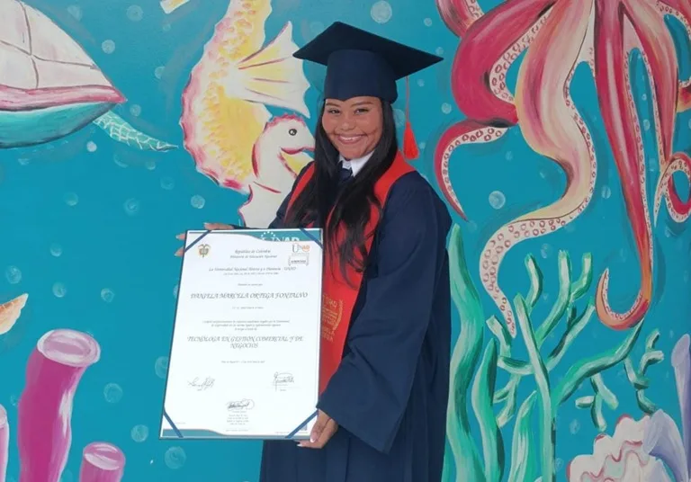 Joven beneficiaria de Becas del Cambio sostiene su diploma de grado feliz por su logro