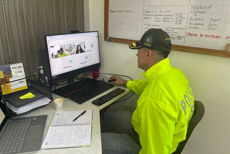 Policia del Gaula sentado frente a un computador en un webinar para docentes sobre extorsión