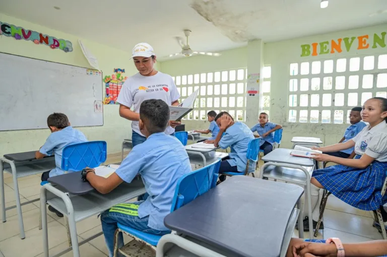 En un salón de clases, la maestra explicando a los estudiantes.