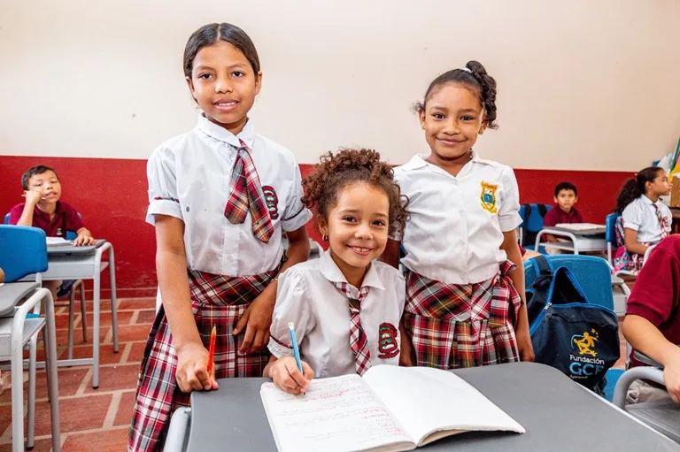 Tres niñas con uniforme de colegio en un salón de clases
