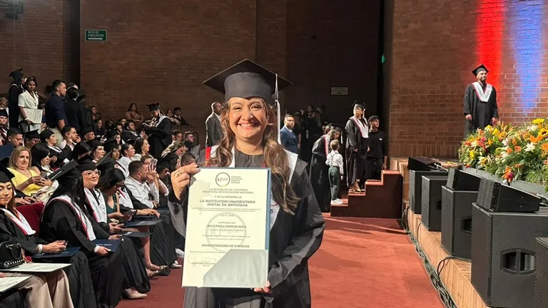 Jovén con un diploma en la mano sonrie feliz en su ceremonia de graduación