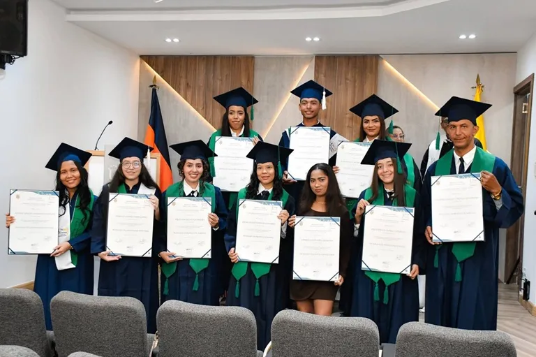 Graduandos vestidos con toga y birrete sostienen felices sus diplomas