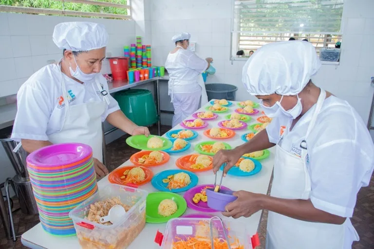 Mujeres en la cocina preparando alimentos para estudiantes