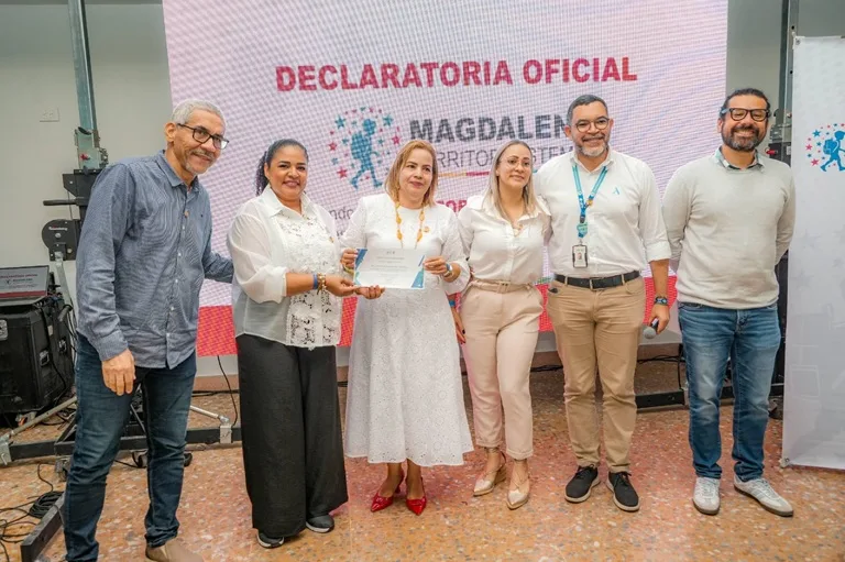 Grupo de seis personas posa en el escenario durante el evento oficial de declaratoria del Magdalena como Territorio STEM+E. Una mujer en el centro sostiene un certificado de reconocimiento mientras es acompañada por representantes de la Secretaría de Educación y aliados del programa